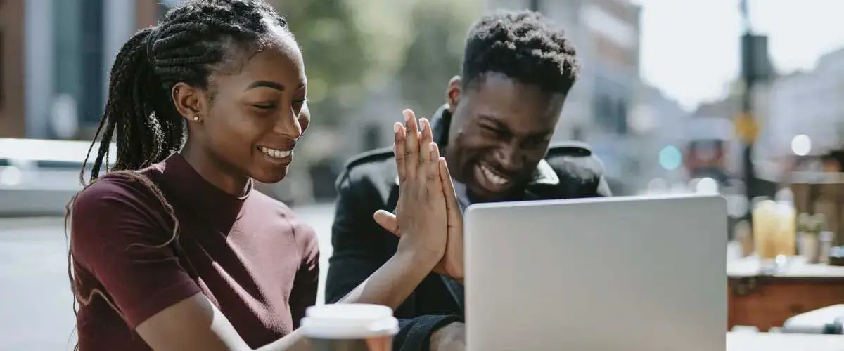 Two students working outside on laptop